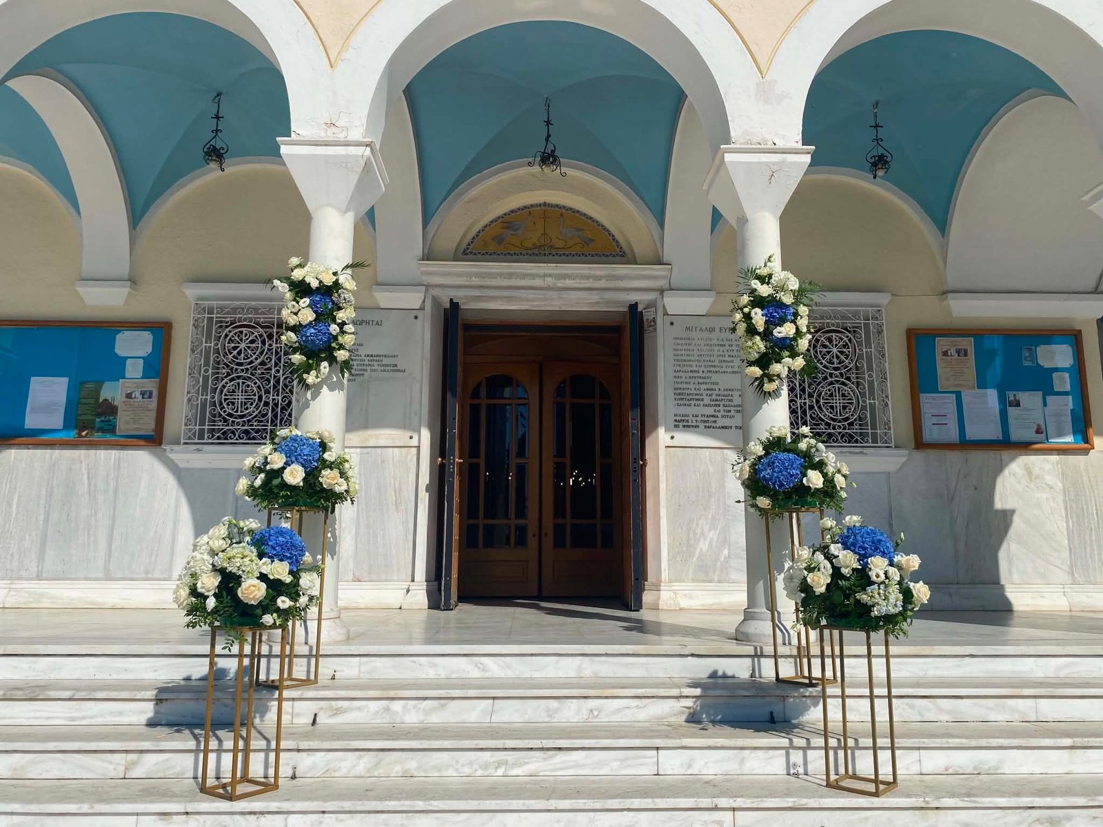 Στολισμός εισόδου εκκλησίας με λευκά τριαντάφυλλα και μπλε ορτανσίες